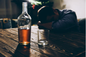 Мужчина лежит на столе с алкоголем
